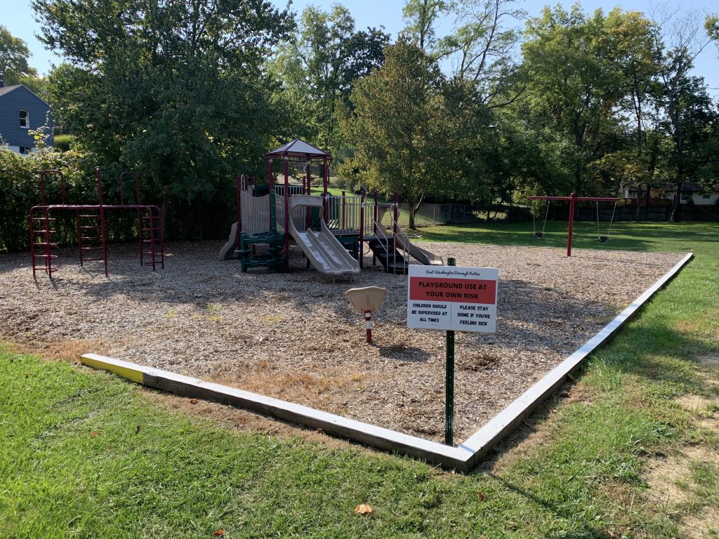 Thayer Street Park playground with a use at your own risk sign.