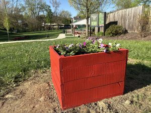 Red planter box with flowers installed in Nicholas Cumer Park